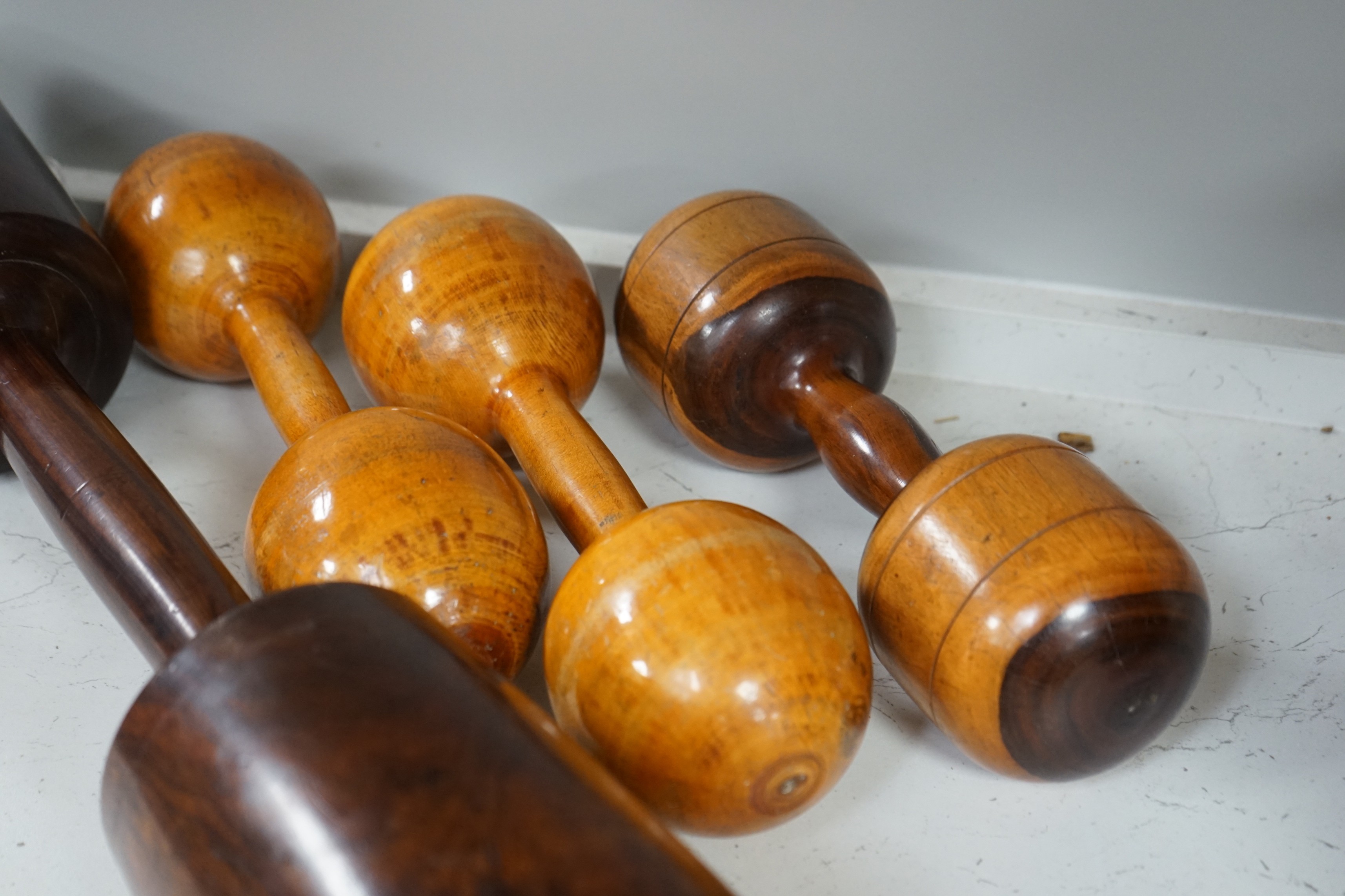 A large treen dumbbell / press together with three wooden American dumbbells by A.G. Spaulding & Bros